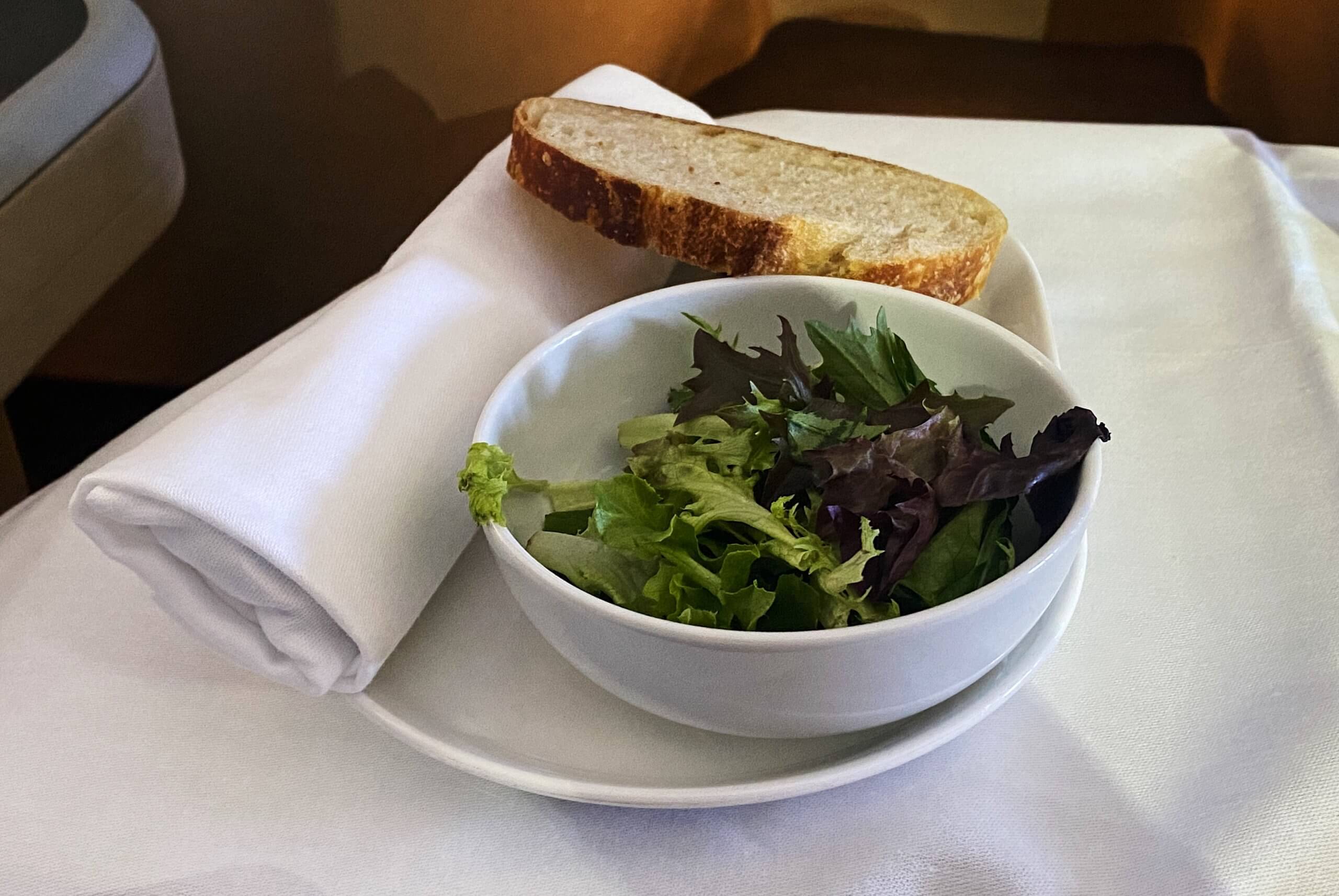a bowl of salad and bread on a plate