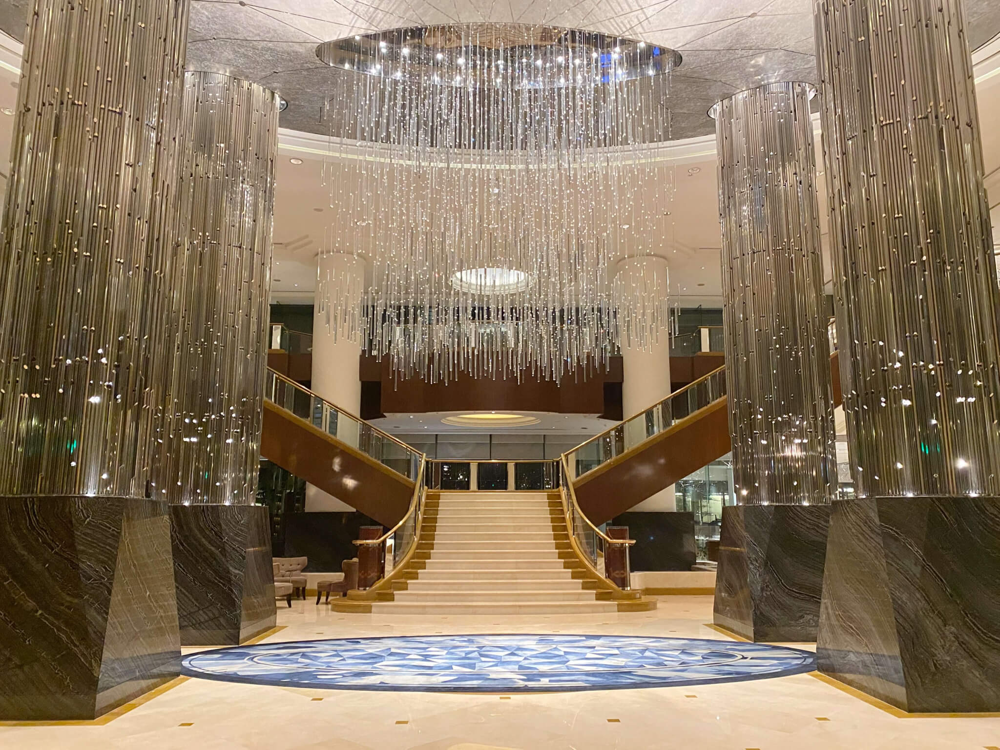 a large staircase with chandeliers and a blue carpet