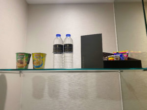 a glass shelf with food and water bottles on it