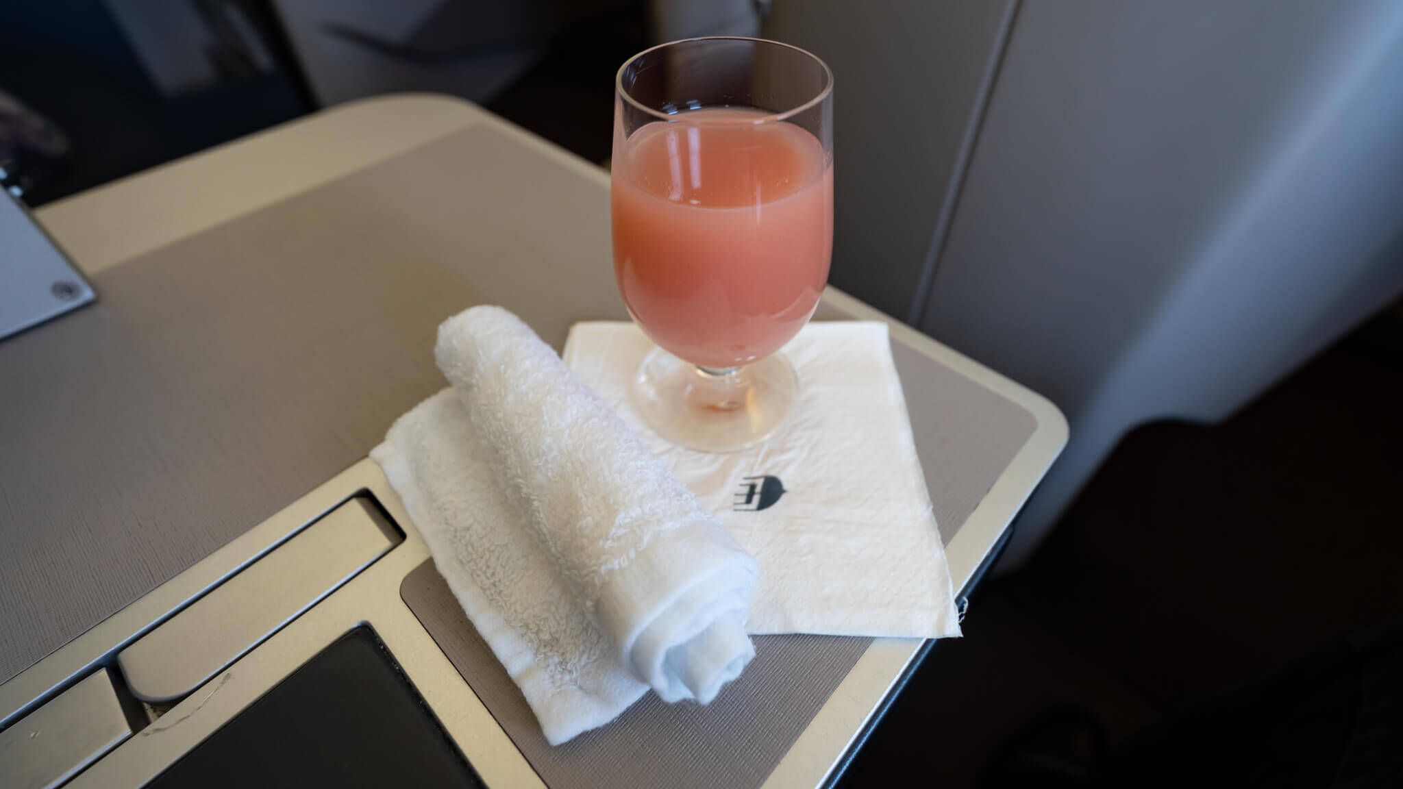 a glass of pink liquid on a white towel on a laptop