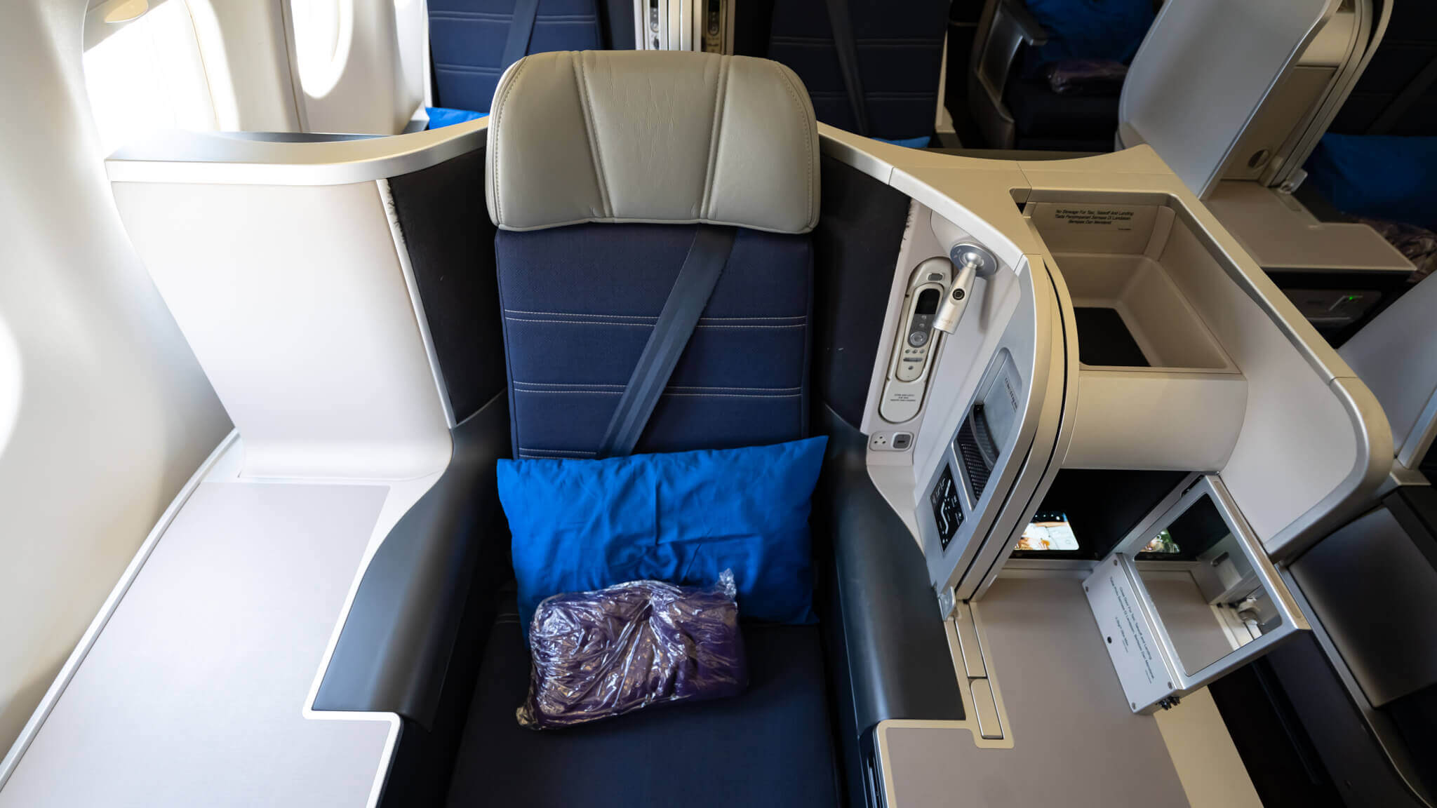 a seat with a pillow and a blue pillow on the back of a plane